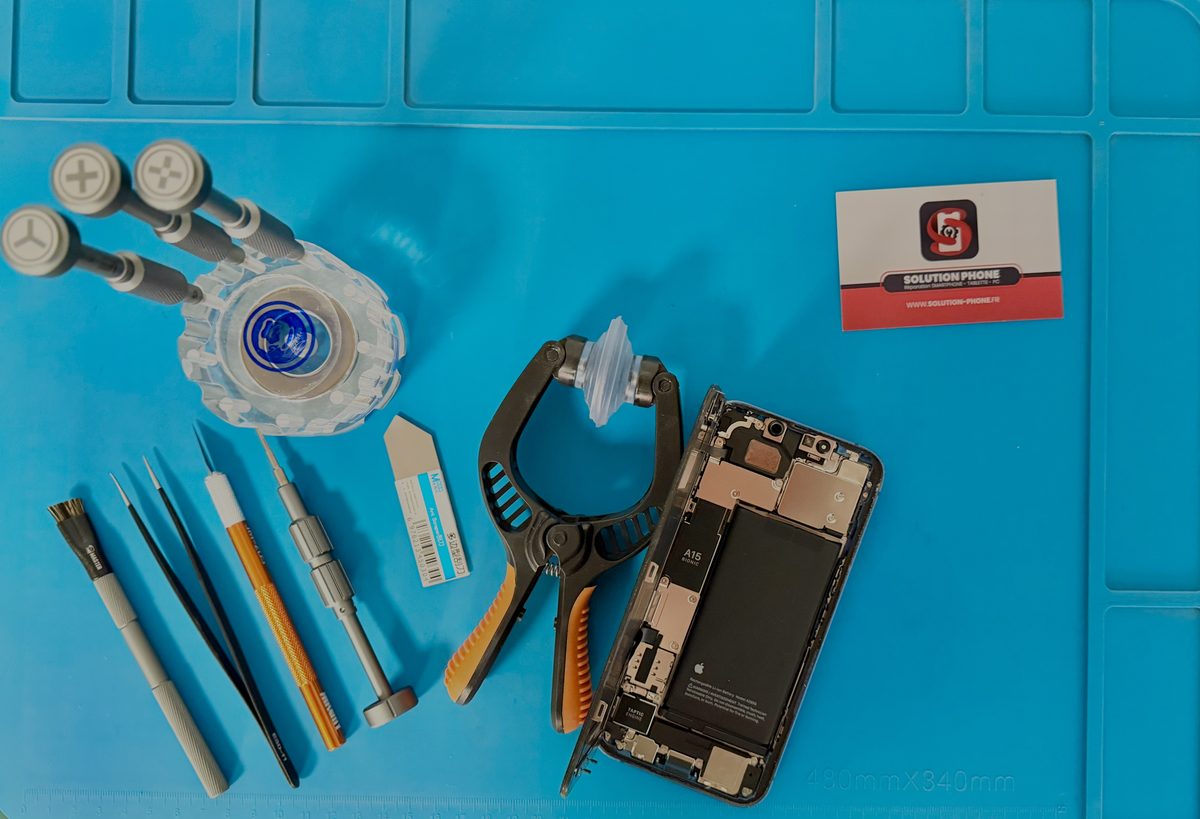 Atelier Solution Phone Mâcon — tapis de réparation bleu avec outils professionnels et iPhone ouvert